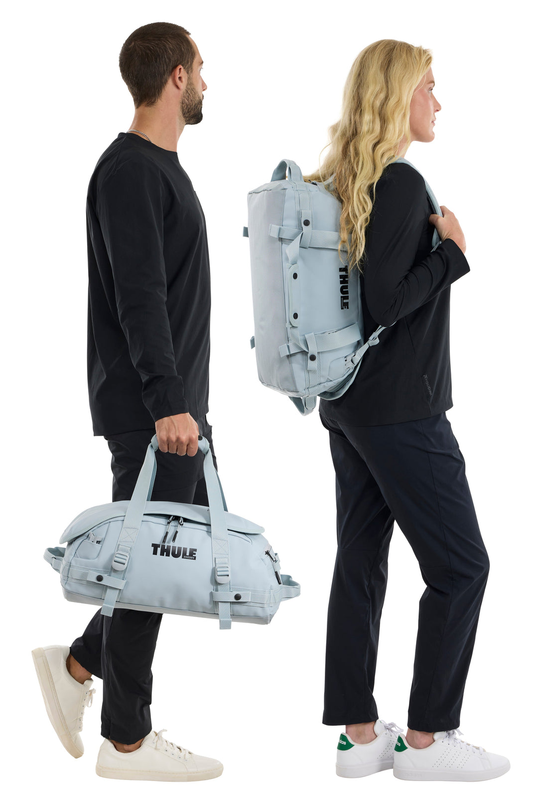 Two people carrying Thule bags, one duffel and one backpack, on a white background.